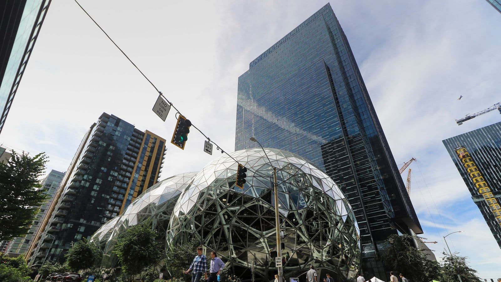 Amazonin Spheres-kasvihuonepallot ja pilvenpiirtäjiä Seattlessa, etualalla kaksi jalankulkijaa katukuvassa.