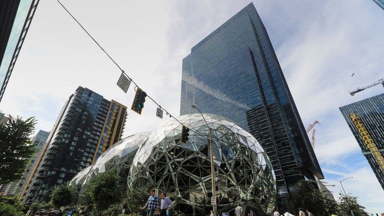 Amazonin Spheres-kasvihuonepallot ja pilvenpiirtäjiä Seattlessa, etualalla kaksi jalankulkijaa katukuvassa.