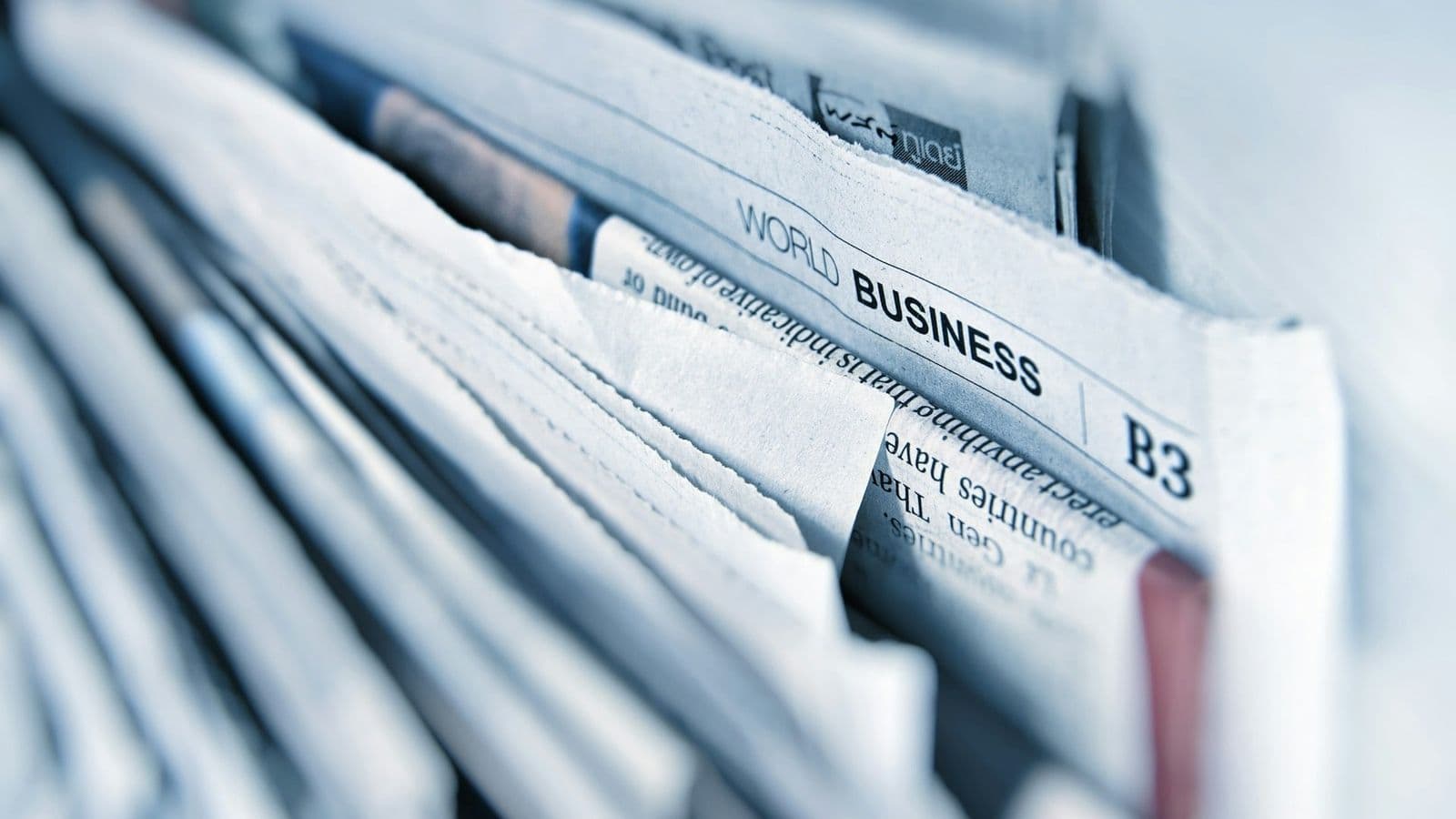 Lähikuva pinosta sanomalehtiä, joiden sivulla näkyy World Business -osasto