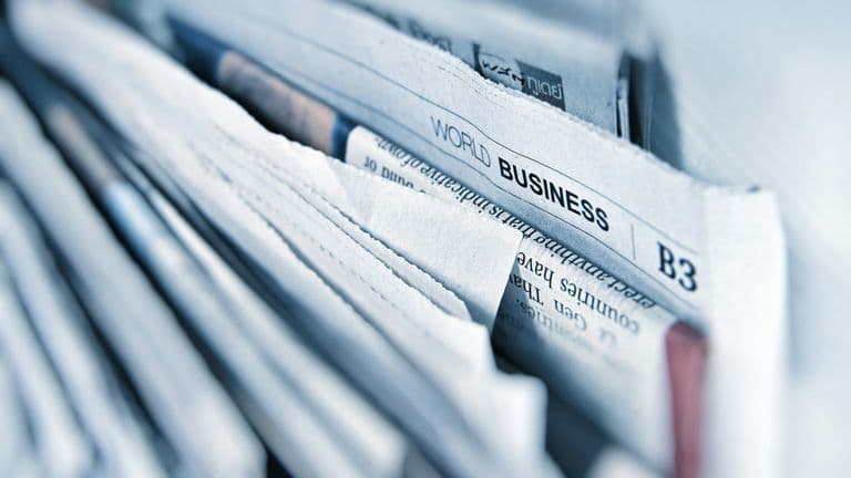 Lähikuva pinosta sanomalehtiä, joiden sivulla näkyy World Business -osasto