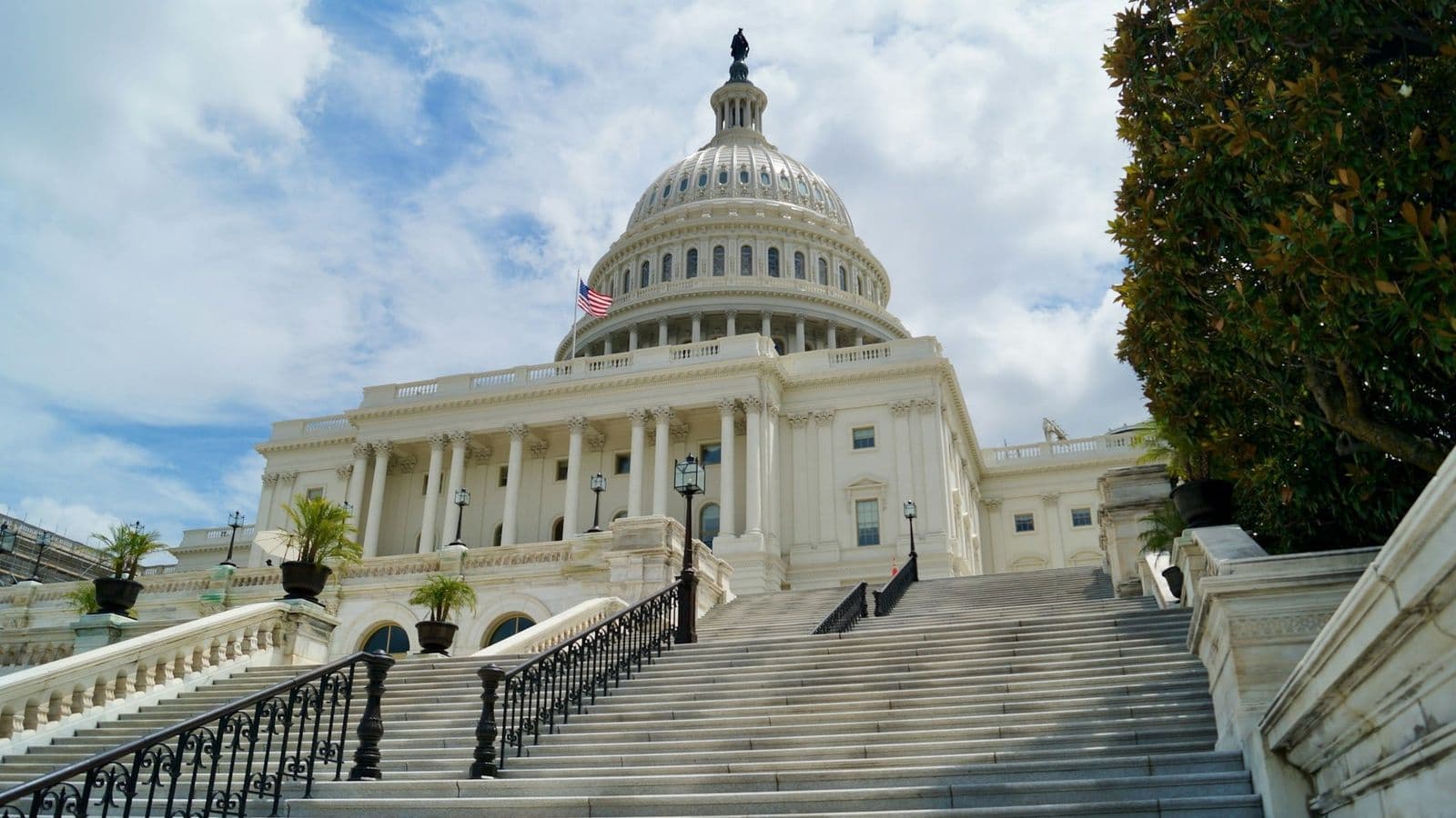 Yhdysvaltain Capitol-rakennus Washingtonissa, etualalla leveät portaat ja taustalla pilvinen taivas