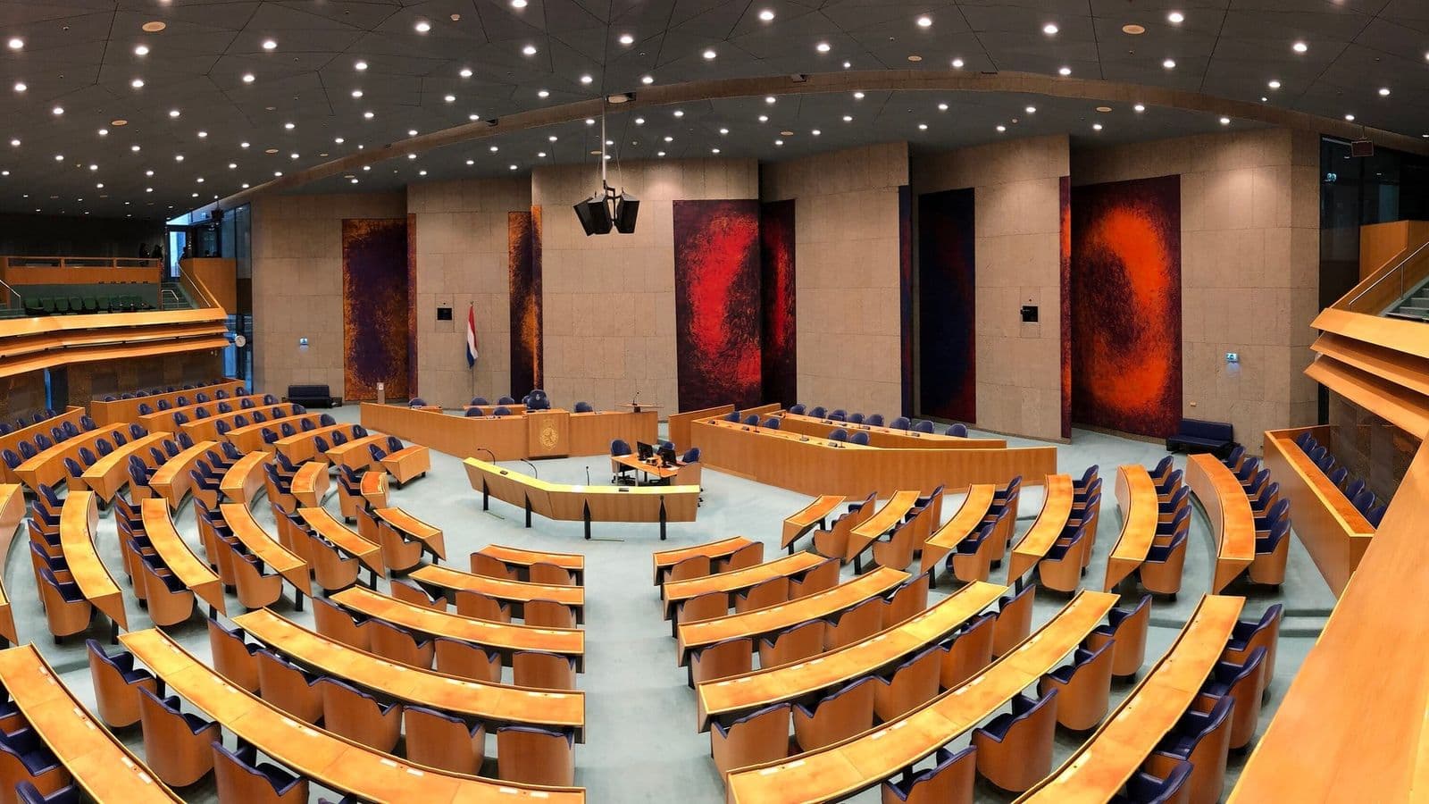 Hollannin edustajainhuoneen täysistuntosali Haagissa, tyhjät puiset penkkirivit ja punaiset seinävaatteet