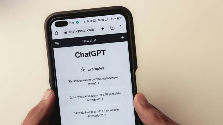 Kädet pitelevät älypuhelinta, jonka selaimessa on ChatGPT:n aloitusnäkymä