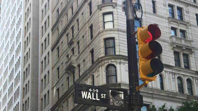 Wall Street -katukyltti ja punainen liikennevalo New Yorkin finanssialueen rakennusten edessä