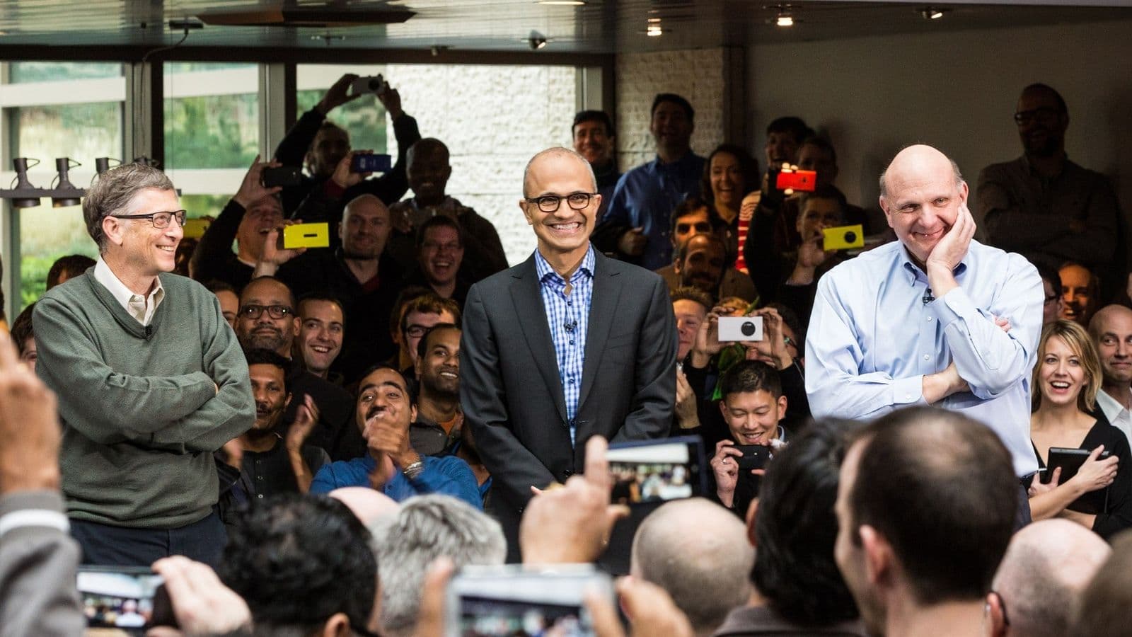 Bill Gates, Satya Nadella ja Steve Ballmer hymyilevät Microsoftin työntekijöiden edessä Nadellan ensimmäisenä CEO-päivänä